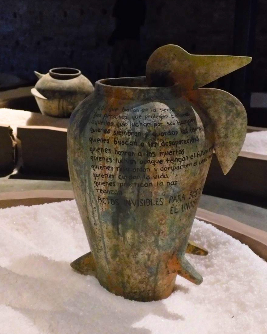 5 of 5, a ceramic vase with writing on the side, sits on salt within a platform on the ground
